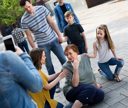People of different ages outdoor helping mature female with pain in heartの写真素材