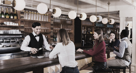 Portrait of positive smiling barman and  people who are standing near bar counter in luxurious restaurant.の写真素材