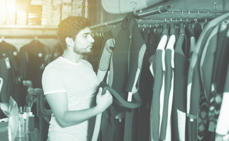 Adult french man holding and choosing suit for surfing in the shop
の写真素材