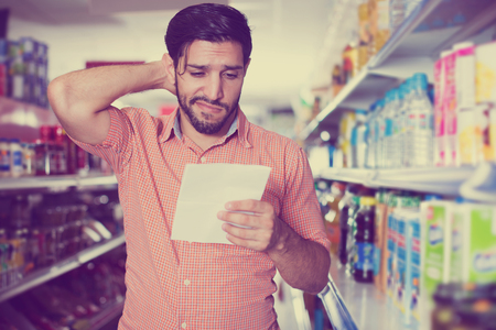 Serious  male with note list for looking goods in market.の写真素材