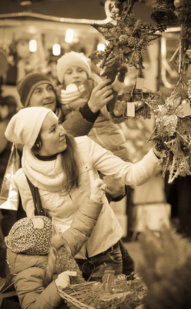 Happy young parents with two little daughters choosing X-mas decorations in market. Focus on girlの写真素材