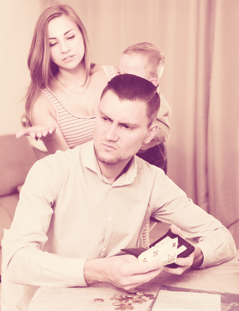 gloomy woman with crying son extorting money from adult man at home の写真素材