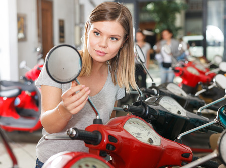 Smiling female is looking on new motobikes in the moto store.の写真素材