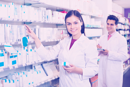 Positive pharmacist and pharmacy technician posing in drugstoreの写真素材