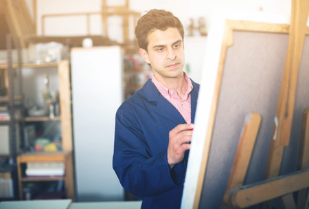 Happy art painter holding artist palette and painting on canvasの写真素材