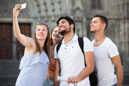 Four friendly travellers making selfie with mobile phoneの写真素材