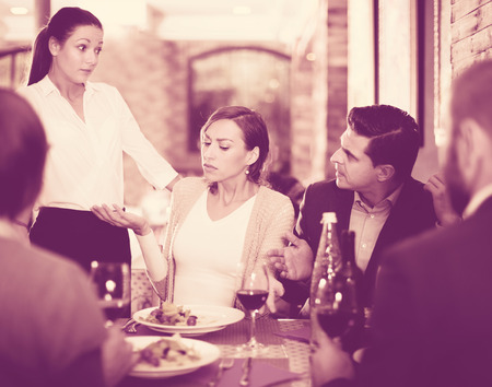 Angry female and male conflict with apologetic waitress about dishの写真素材