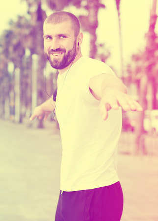 Athletic male performs warm-up exercises before trainingの写真素材