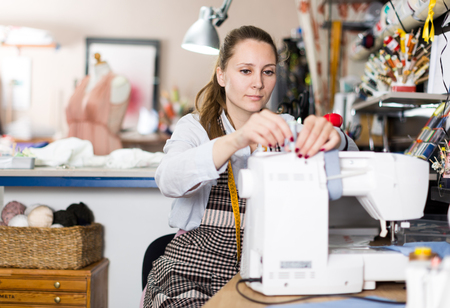 Woman is working with sewing machine for new fashion collection in the workshop.の写真素材