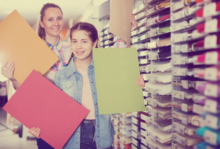 Pretty mother and daughter  choosing paper for drawing in art shopの写真素材