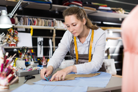 Portrait of woman designer who is doing new pattern for dress in the workshop.の写真素材
