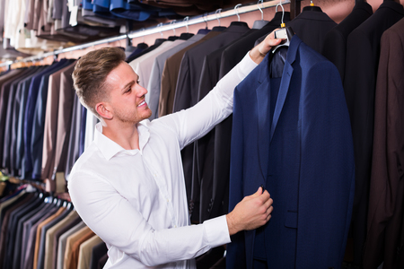 Young male customer examining suits in menâs cloths storeの写真素材