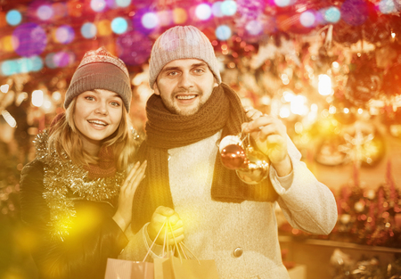 Portrait of joyful young couple with Christmas toys at fair outdoorの写真素材