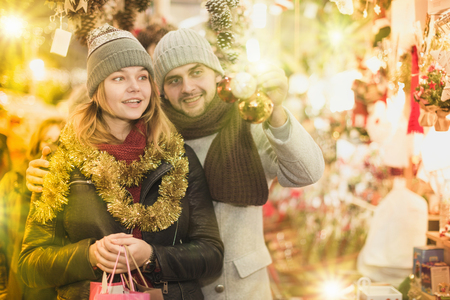 Positive young couple buying decoration at Christmas Fair outdoorの写真素材
