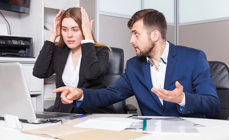 Frustrated female and male sales managers working in showroom, looking at laptop monitorの写真素材