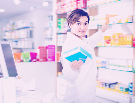 Beautiful pharmacist offering reliable medicine in pharmacyの写真素材