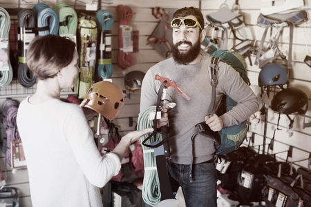 Young man and woman buying alpinism equipment in sports equipment storeの写真素材