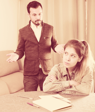 Young father arguing with his teenage daughter at homeの写真素材