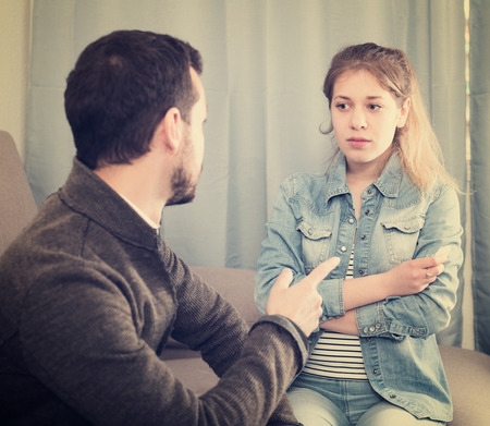 Young father arguing with his teenage daughter at homeの写真素材