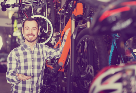 smiling man in sports workshop mounts bike using special toolsの写真素材