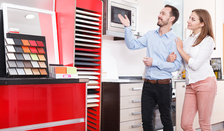 Loving happy couple choosing kitchen furniture materials for a their apartment. Focus on both personsの写真素材