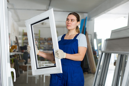 Portrait of woman worker who is standing with window frame in the pvc workshop.の写真素材