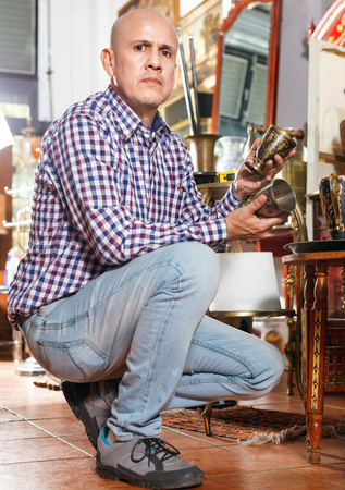 Portrait of positive   successful owner of antiques shop among vintage thingsの写真素材