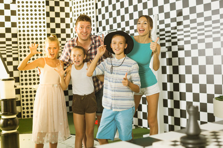 Parents with their children are satisfied after visit of escape room stylized under chessboard.の写真素材