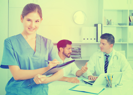 Smiling young female doctor writing notes on clipboard in clinicの写真素材