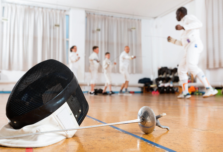 Closeup of fashionable  stylish fencing mask and rapier on floor in gymの写真素材