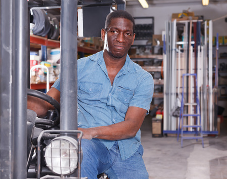 Happy African American worker on forklift in building materials storeの写真素材