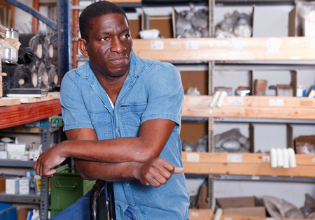 Portrait of cheerful  confident African American man standing among shelves with materials for renovation works in building hypermarketの写真素材
