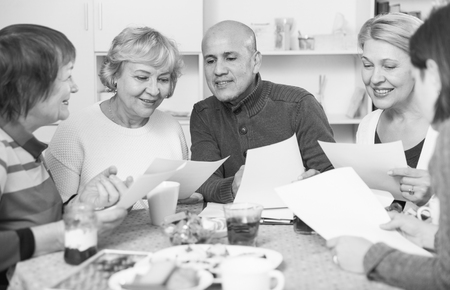 Mature friends are talking about documents at home.の写真素材