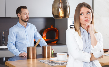 Upset girl dont speaking after discord with man standing behind in kitchenの写真素材