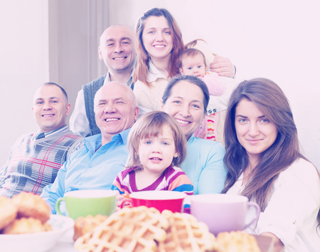 Portrait of happy three generations family posing together over tea at homeの写真素材