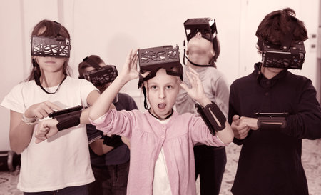 Enthusiastic  cheerful positive smiling children in virtual reality glasses in quest room