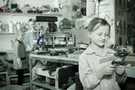 Glad girls teenagers practicing their skills at wood carving during arts and crafts classの写真素材