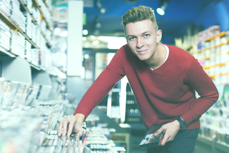 Glad surprised man in search of movies on DVD at storeの写真素材