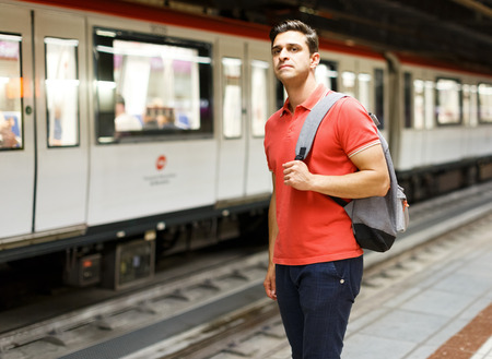Man is looking on railway and waiting train on platform in the underground.の写真素材
