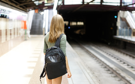 Woman is standing on platform and waiting train in the underground.の写真素材