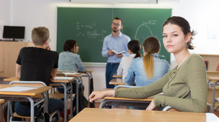 Portrait of girl who is posing at the desk in the class.の写真素材