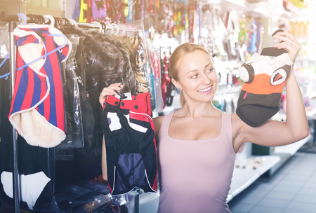 Young happy  girl choosing for best clothes for dog in pet shopの写真素材