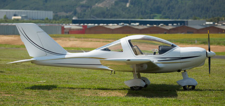 Light sport airplane standing on green grass of airfield on summer day