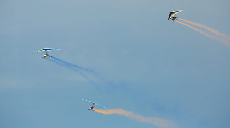 Flex-wing trikes flying in sky during air show leaving colored smoke trails