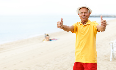 Satisfied active mature man posing near ocean and 
giving thumbs upの写真素材