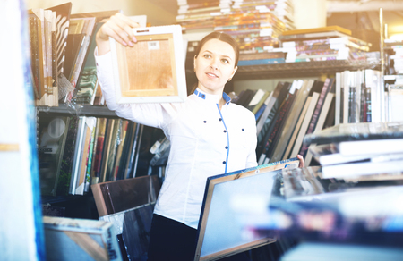 Happy positive smiling woman is choosing new picture for her home in the store.の写真素材