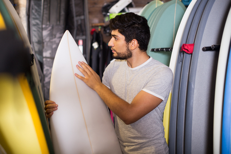 portrait of professional man choosing board for surfing in the shopの写真素材