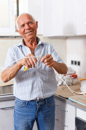 Skillful older man engaged in renovation work indoorsの写真素材
