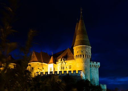 Impressive night landscape with illuminated medieval Corvin Castle on elevated rock, Hunedoara, Romaniaの写真素材