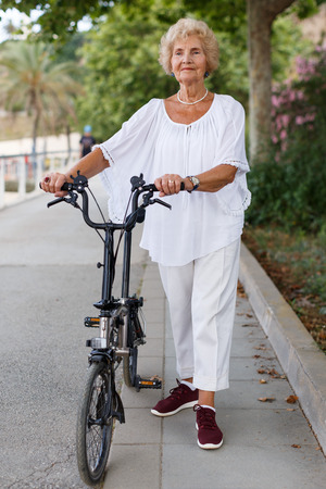 Portrait of casual senior woman going to bike at summer dayの写真素材